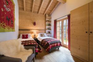 two beds in a room with wooden walls at Chalet Alexia in La Tzoumaz