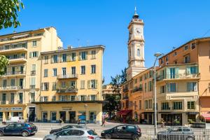 a clock tower in the middle of a city with cars at RIVIERA COZY - Place Massena in Nice