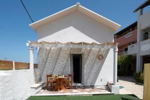 a small white house with a table and chairs at Elves Studios& Apartment's SIDARI in Sidari