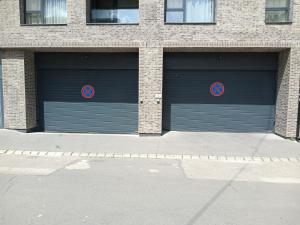 two garage doors in a brick building with twoairs at Cloé Apartman by Noir Hotel in Szeged