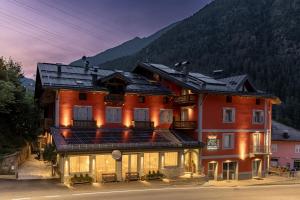a large red building with a mountain in the background at Hotel Garnì Zanella in Fucine