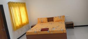 a bedroom with a bed with yellow sheets and a window at Hiran Holidays in Sasan Gir