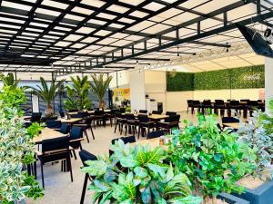 ein Restaurant mit Tischen und Stühlen und Topfpflanzen in der Unterkunft Resort Leon Beach in Mamaia Nord – Năvodari