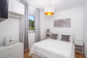 a white bedroom with a bed and a window at House KID in Bribir +37 photos