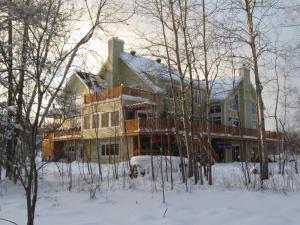 a large house in the snow with trees at Le Gite Du Hu-Art in Quebec City