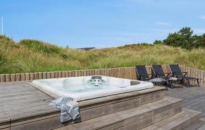 a bath tub sitting on a wooden deck with chairs at 9 Bedroom Lovely Home In Ringkøbing in Søndervig