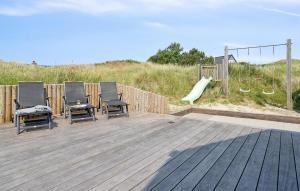 a deck with chairs and a slide and a playground at 9 Bedroom Lovely Home In Ringkøbing in Søndervig +35 photos