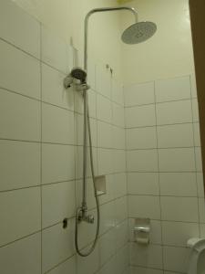 a shower in a white tiled bathroom at Wana Guest House in Rubirizi +18 photos