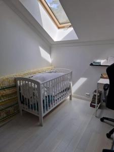 ein Babybett in einem Zimmer mit Dachfenster in der Unterkunft Zapraszamy w nasza słoneczna Przestrzeń in Søgne
