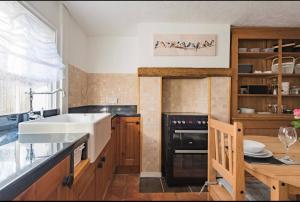 a kitchen with a sink and a stove at Brook Cottage in Temple Ewell +13 photos