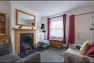 a living room with a fireplace and a mirror at Brook Cottage in Temple Ewell