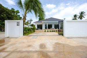 a house with two white doors and a palm tree at Thala Villa Koh Samui in Nathon Bay