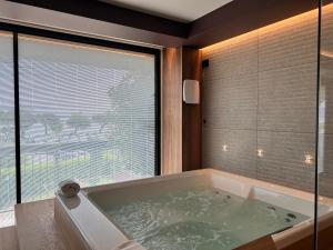 a bath tub in a bathroom with a large window at Alevic Hotel Sirmione in Sirmione