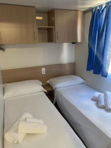オリヴェーリにあるBaia del Principe MobilHomeの小さな部屋のベッド2台(タオル付)