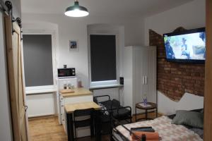 a living room with a bed and a tv on the wall at Stargard centrum Apartamenty Zajazd in Stargard