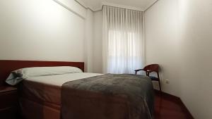 a small bedroom with a bed and a window at O Xardín Termal in Ourense