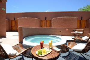a patio with a pool with chairs and a table with drinks at Hotel Pascual Andino in San Pedro de Atacama