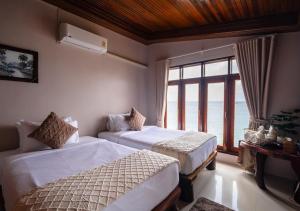 a bedroom with two beds and a large window at Dusit Buncha Koh Tao by Riya Group in Ko Tao