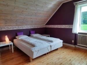 a bedroom with a white bed with purple walls at Ferienhaus Björkebo in Stöllet