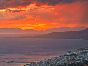 a sunset over the ocean with a city at Heavenly View Peach in Lákhion