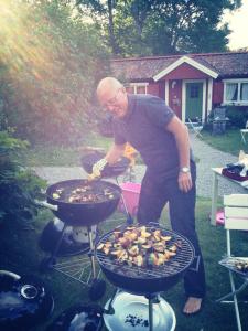 a man is cooking food on a grill at Stora Djulö Vandrarhem in Katrineholm