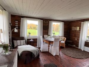 a living room with a table and chairs and windows at Lavendeltorpet in Häggum