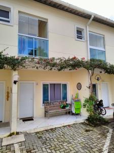 une maison avec un banc devant dans l'établissement CASA EM CONDOMÍNIO ARBORIZADO PERTO DA PRAIA Confortável e Espaçosa, à São Sebastião