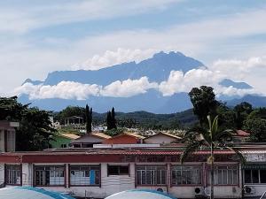 a mountain in the background of a town with a building at WISMA ORCHID HOMESTAY Tuaran in Tuaran