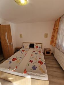 a bedroom with a bed with a floral bedspread at Pensiunea Armonia in Băile Herculane