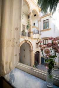 un vaso di fiori su un davanzale con un edificio di Palazzo Santa Ninfa - Luxury Mansion a Palermo
