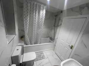 a white bathroom with a toilet and a shower at Big new house! 5BDR, sleeps 13, with parking in Carrington +24 photos