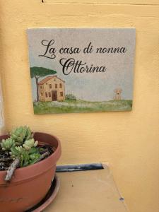 a painting of a house and a potted plant on a wall at La casa di nonna Ottorina in Venturina Terme