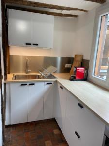 eine Küche mit weißen Schränken und einer Spüle und einem Fenster in der Unterkunft La chambre de Baucis in Tours