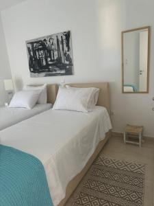 a bedroom with two white beds and a mirror at Artist Home in Porto Rafti
