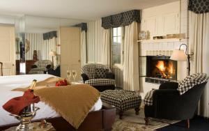 a bedroom with a bed and chairs and a fireplace at The Manor on Golden Pond in Holderness