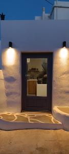 eine Tür in der Seite einer weißen Wand mit Lichtern in der Unterkunft Little House in Káto Petálion