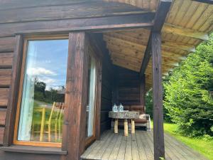 a wooden cabin with a table on a deck at Pod dobrym adresem- domek pod lasem in Cisna +8 photos