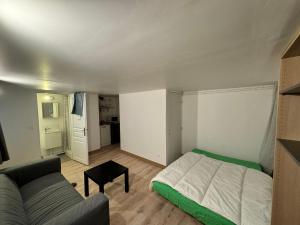 una piccola camera da letto con un letto e un divano di Stade de France Appartement a Saint-Denis