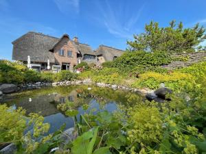 a large house with a pond in the yard at Ulenhof Appartements in Wenningstedt