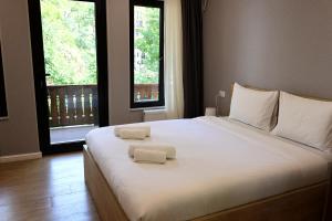 a bedroom with a large white bed with two towels on it at Greenwood in Borjomi