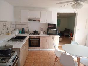 una cucina con mobili bianchi e un tavolo e una sala da pranzo di La Case des Jacques a Saint-Joseph