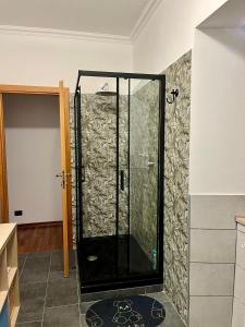 a glass shower in a room with a wall at Lupin House in SantʼAngelo Romano