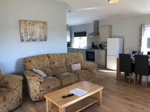 a living room with a couch and a table and a kitchen at Nightjar Lodge - Adults Only in Lackford