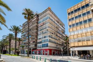a tall building with palm trees in front of it at La Gaviota in Torrevieja