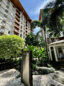 un panneau devant un grand bâtiment avec des arbres dans l'établissement cozy2ndhomeFRM, à Manille
