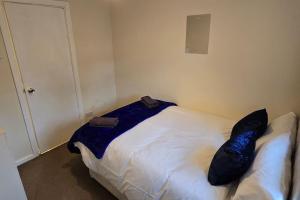 a bedroom with a white bed with black pillows on it at Eastpark 5 bdrms Walk to O2 Apollo and City in Manchester