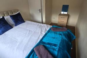 a bedroom with a large white bed with blue pillows at Eastpark 5 bdrms Walk to O2 Apollo and City in Manchester