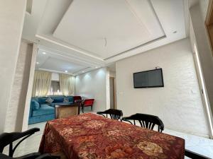 a bedroom with a bed with chairs and a blue couch at Bel Appartement avec terrasse à Dahomey City Bouznika Plage in Kasba Bou Hamira