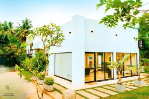 a white house with trees in front of it at The Ivy Lake in Anuradhapura