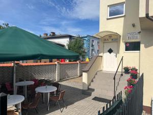 a patio with tables and a green umbrella at Tawerna Michałowscy in Mielno